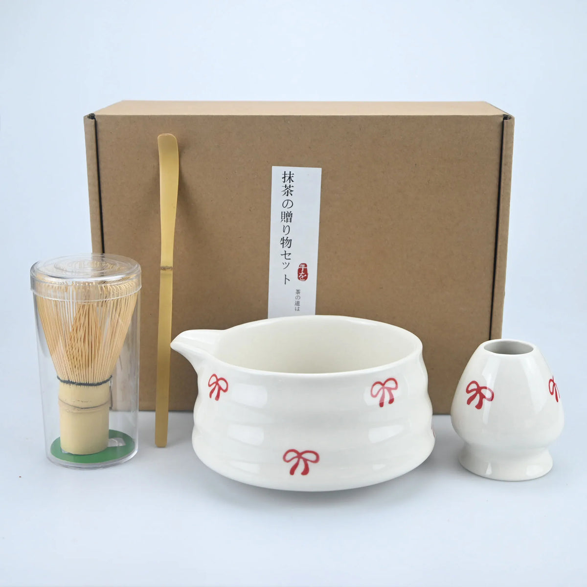 Matcha ceremony set with spouted ceramic bowl, bamboo whisk and red bow