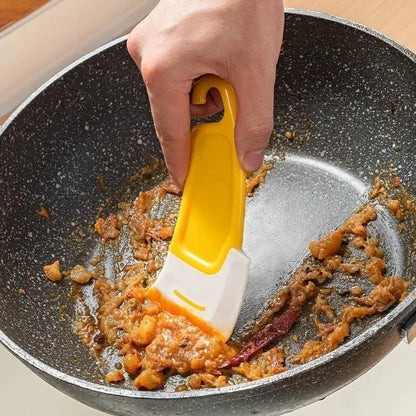 Silicone scraper lifting food residue from a frying pan