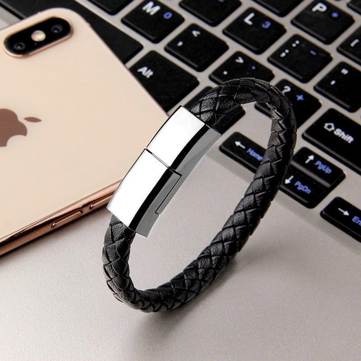 Black braided charging bracelet beside a phone